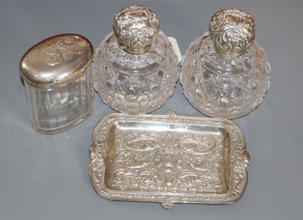 A pair of Edwardian repousse silver mounted cut glass scent bottles, Birmingham, 1905, 11.8cm, a silver pin tray & mounted jar.